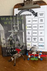The book Fugitive Telemetry is standing next to two wind up robot toys.