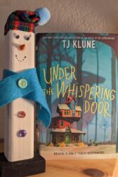 The book, "Under the Whispering Door" by TJ Klune standing next to a wooden snowman.