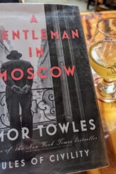 The book, "A Gentleman in Moscow" by Amor Towles next to a hard cider drink from Serpentine Cider.