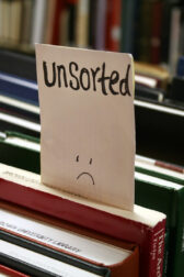 Rows of books. A note that reads "unsorted" is sticking out of one volume.