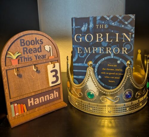 The book, "The Goblin Emperor" by Katherine Addison standing inside a crown, next to a sign that says, "Books read this year" and a number three hanging below.